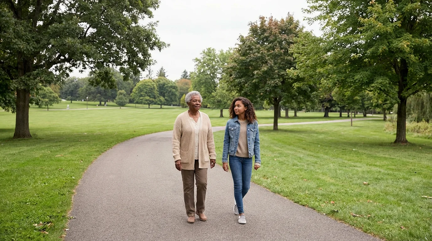 An elderly grandmother and her granddaughter walking and talking peacefully in a large park.