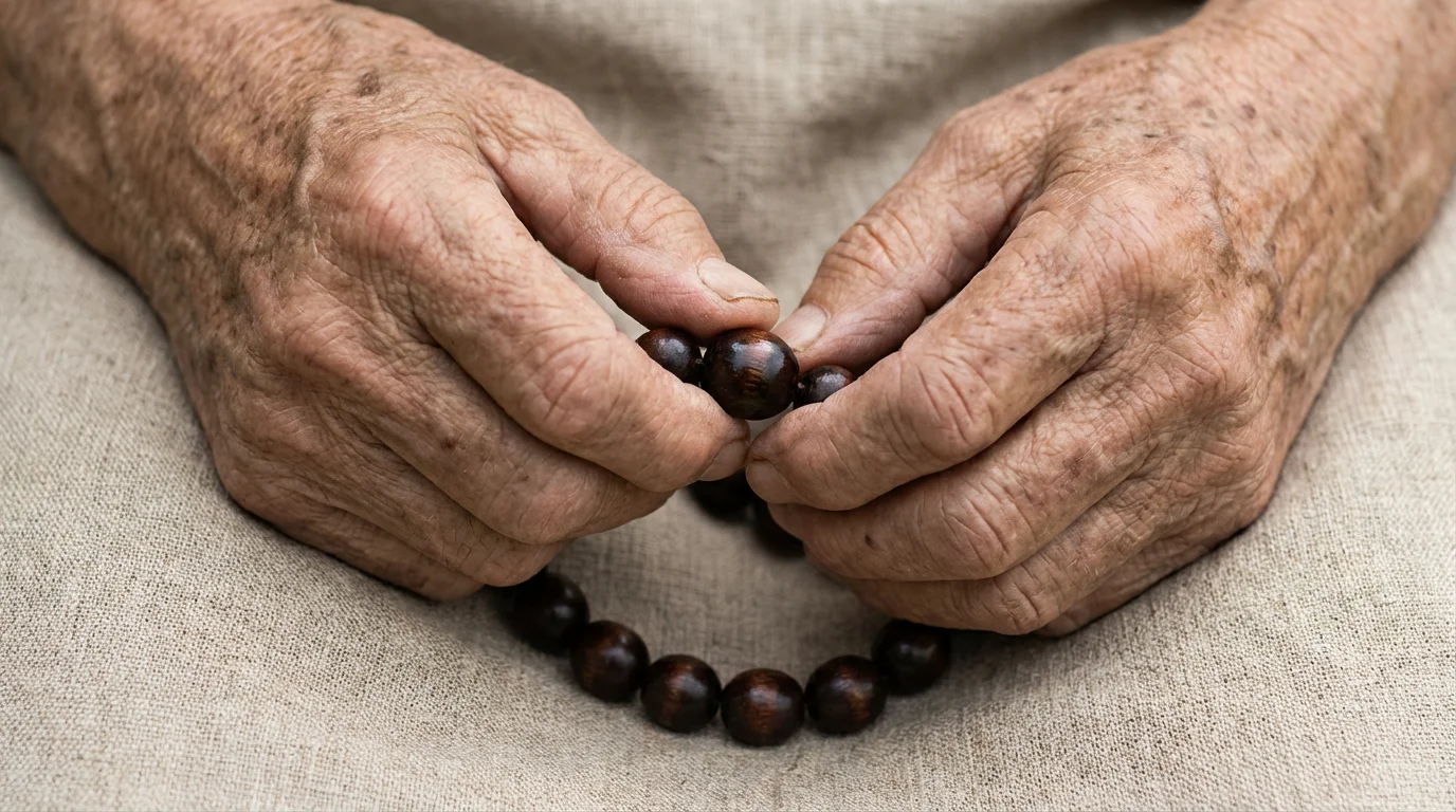 Close-up macro photo of a senior's hands holding wooden meditation mala beads.