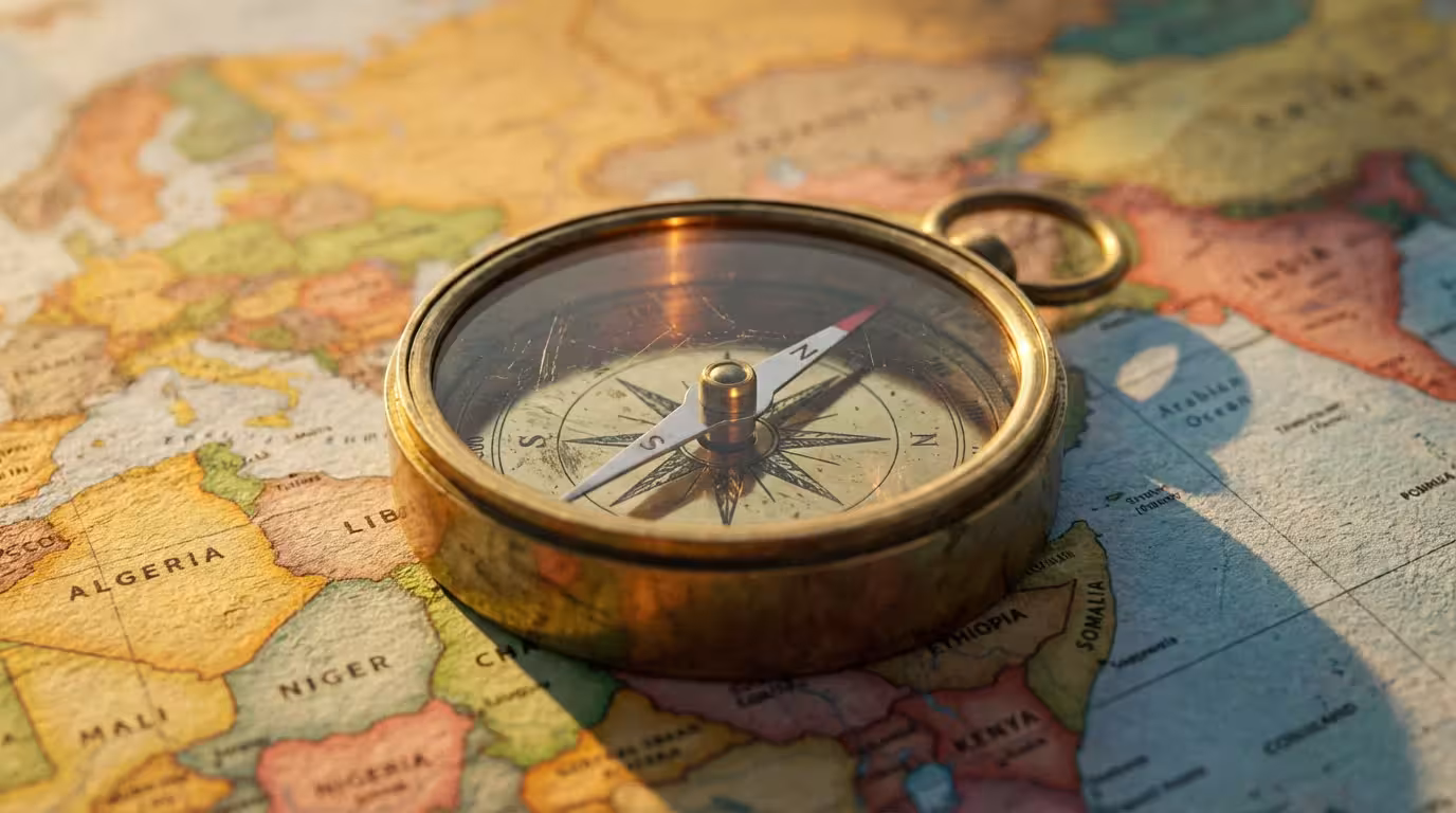 Close-up macro photo of a vintage brass compass on a world map at sunset.