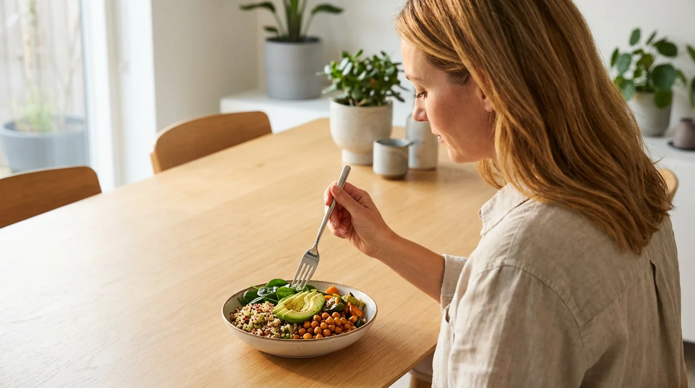 Over-the-shoulder view of a woman mindfully observing a healthy and colorful meal.